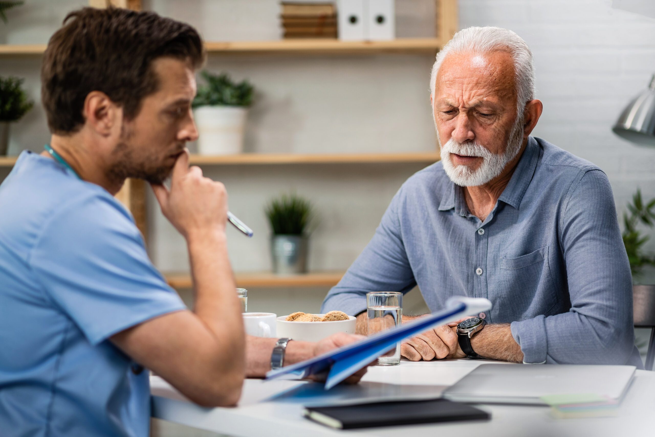 Senior man discussing medical reports with a doctor during an appointment in a modern office setting.